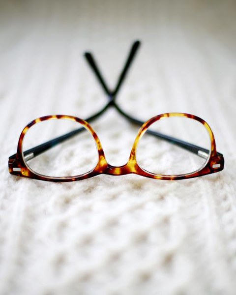 Tortoiseshell spectacle frames resting on a cream knitted throw